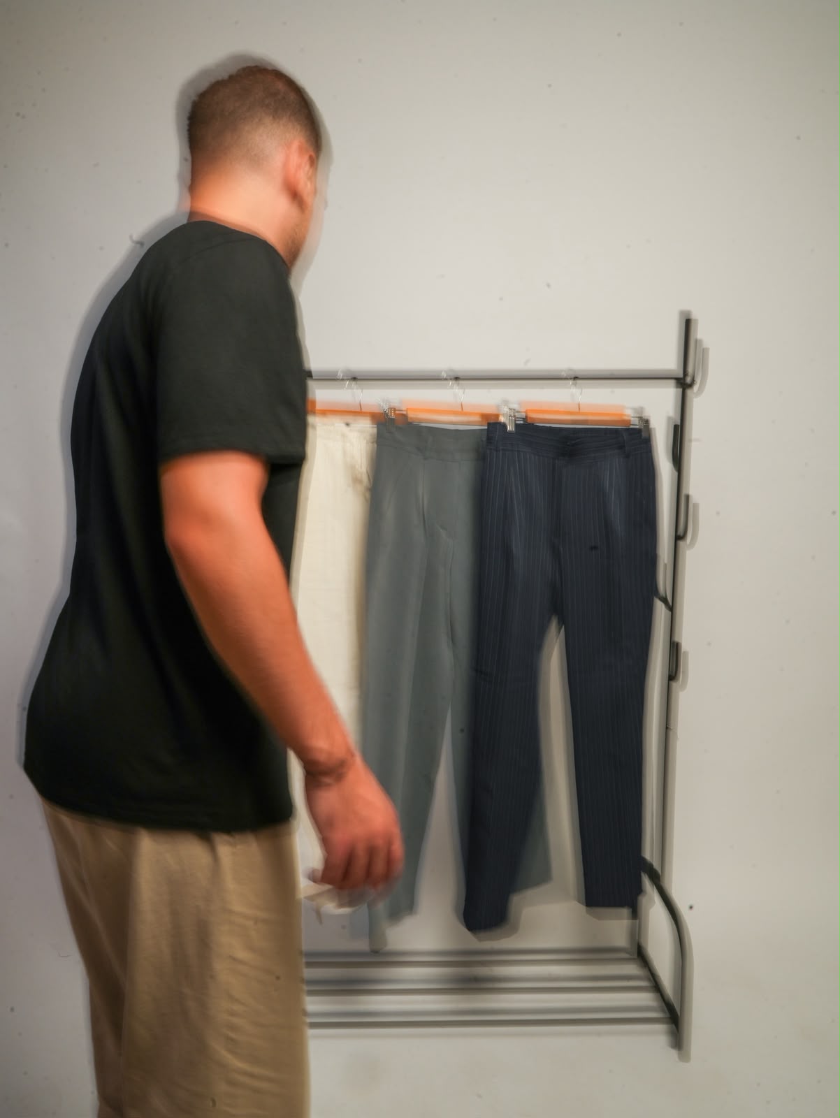 Three pairs of trousers hanging on a studio rack